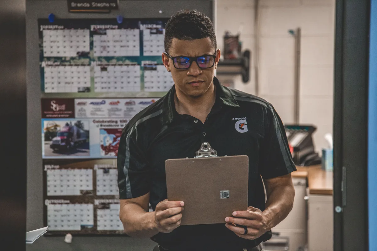 Worker reviewing a clipboard at an industrial workplace.